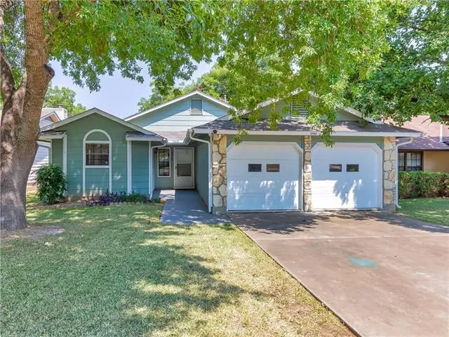a house with a driveway and trees in front of it