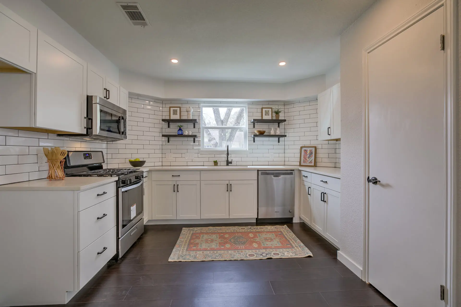 a kitchen with white cabinets and wood floors