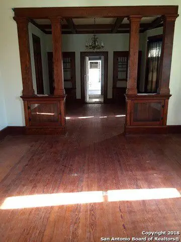 an empty room with wooden floors and a chandelier