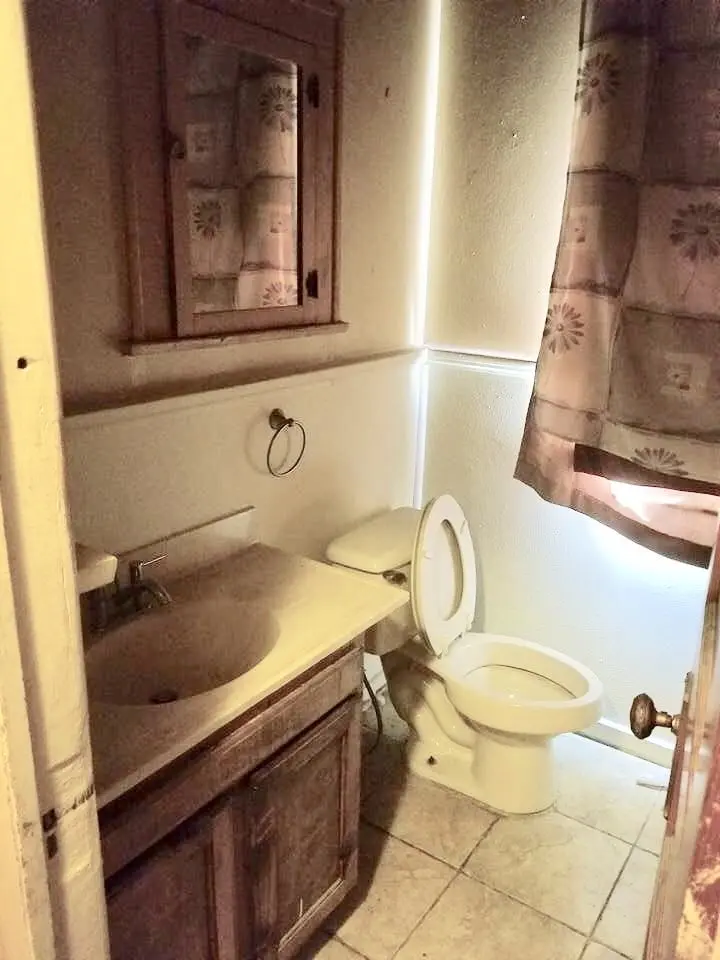 a bathroom with a toilet, sink, and shower curtain