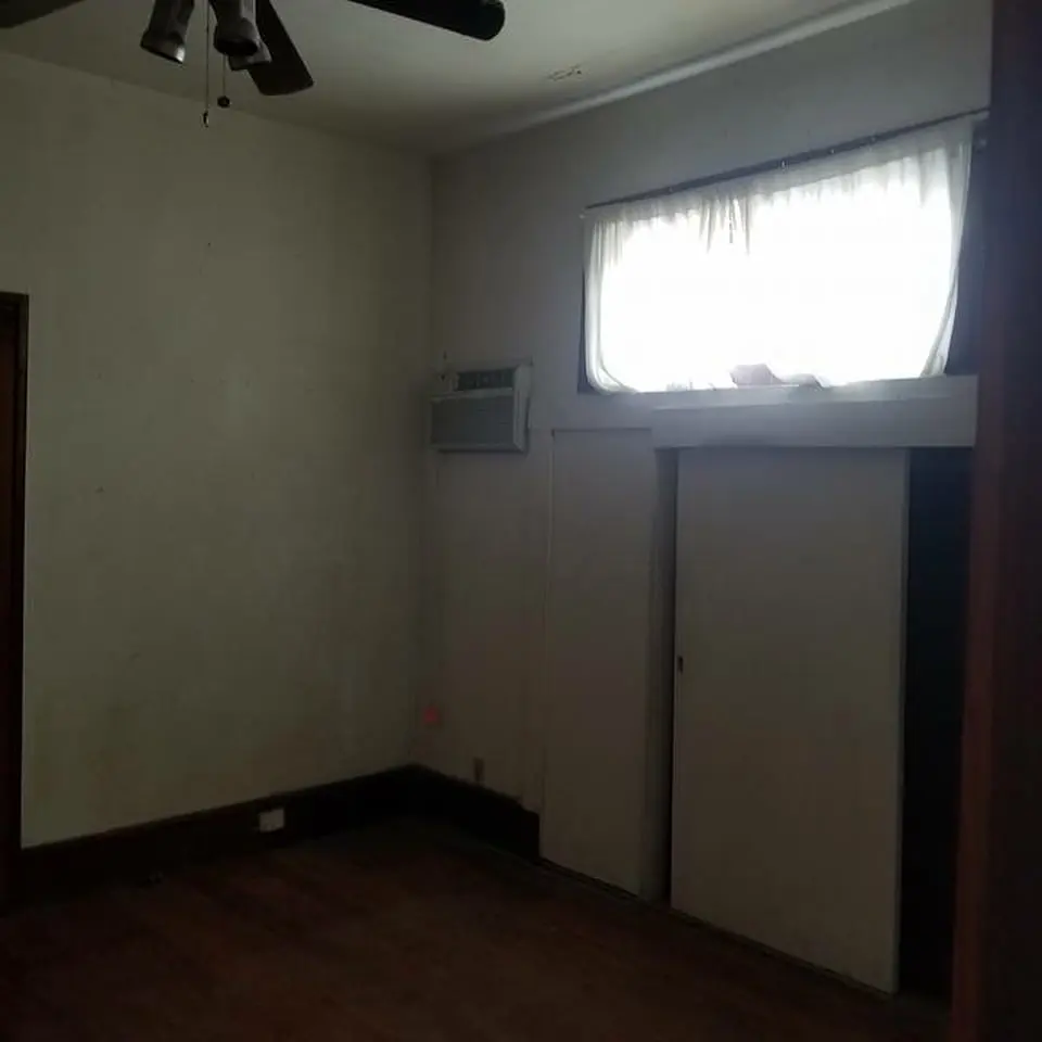 an empty room with a ceiling fan and a window