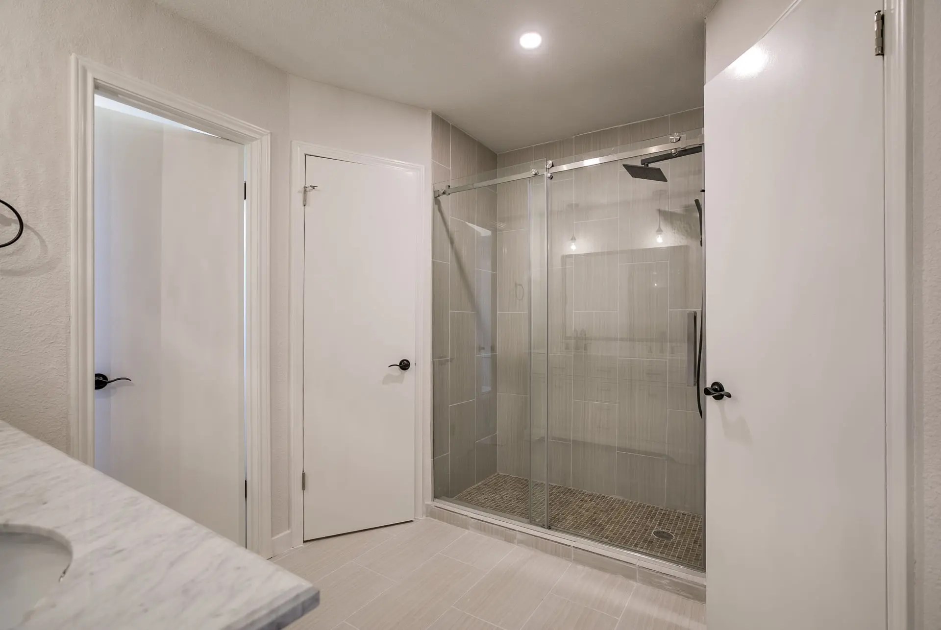 a white bathroom with a walk in shower next to a sink