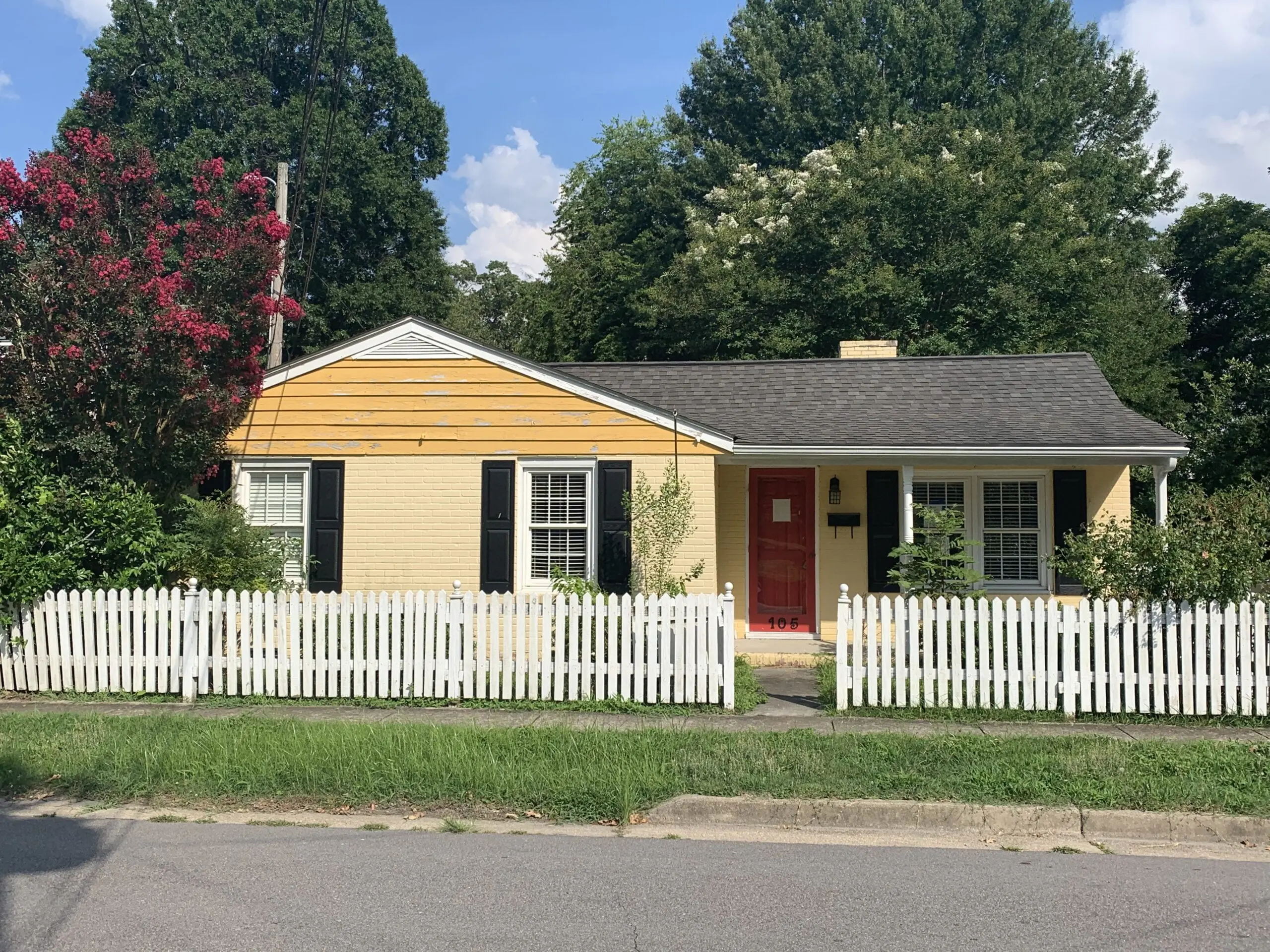 a yellow house with a white picket fence