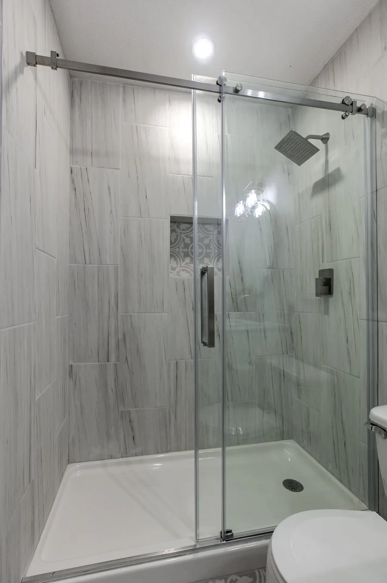 a white toilet sitting next to a walk in shower