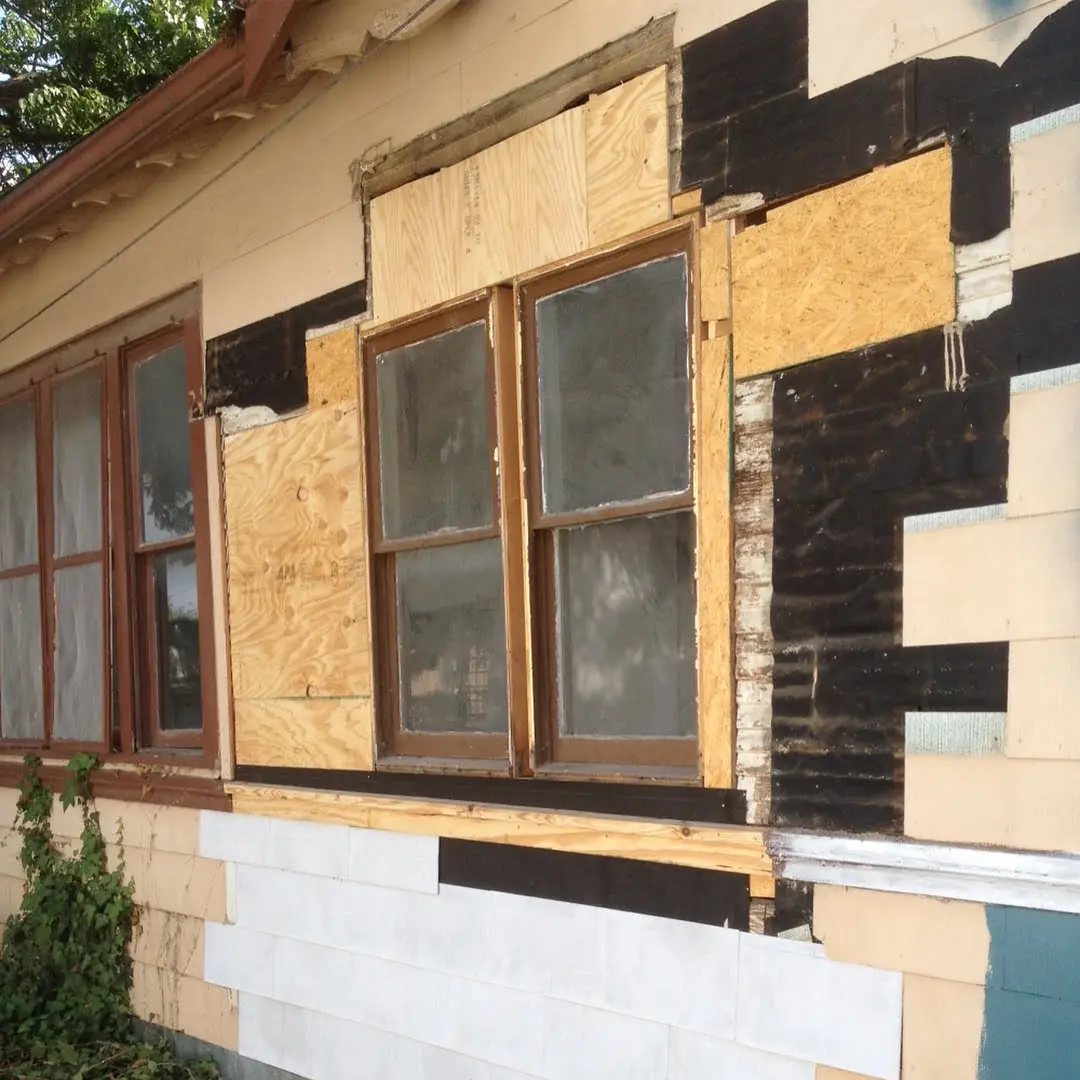 a house with boarded up windows and siding