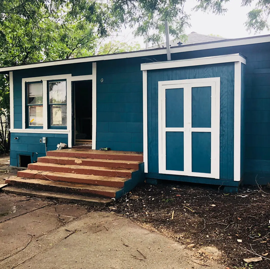 a small blue house with a porch and steps