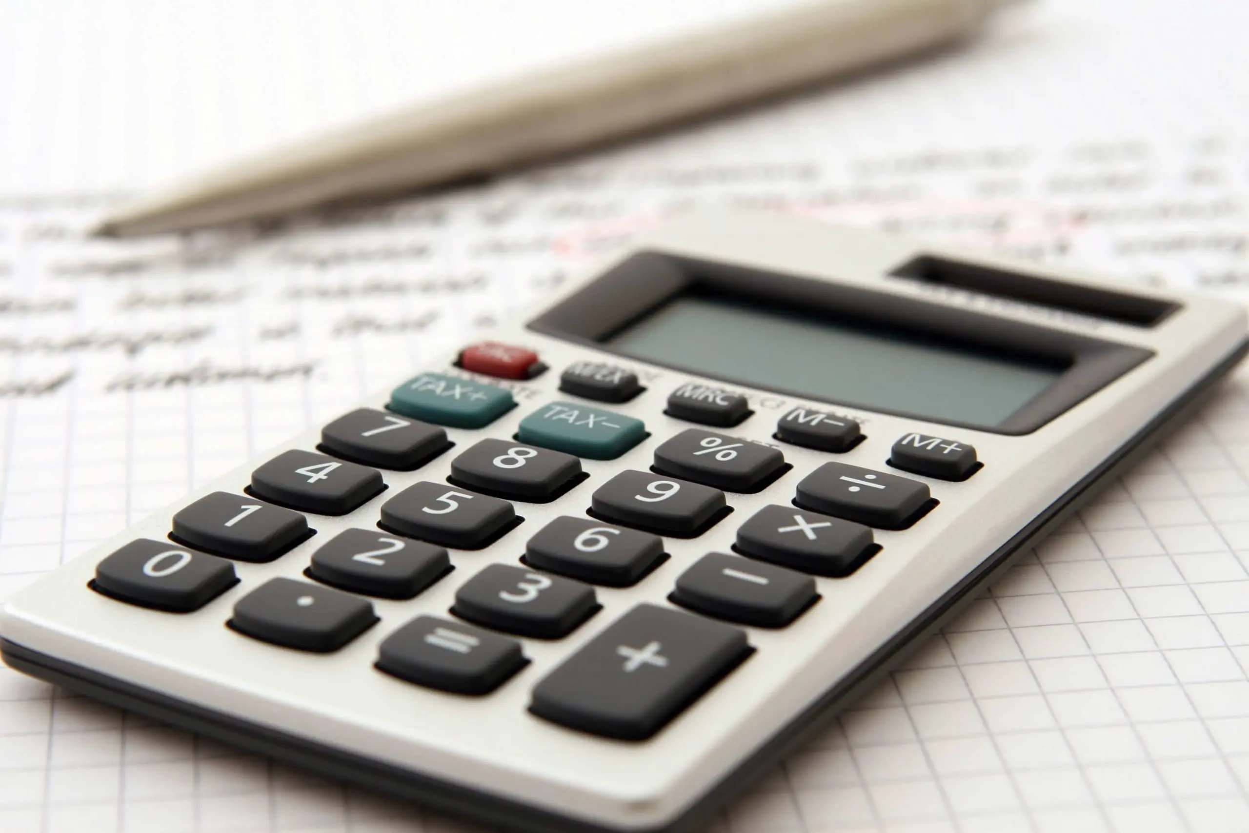 a calculator is sitting on a piece of graph paper next to a pen