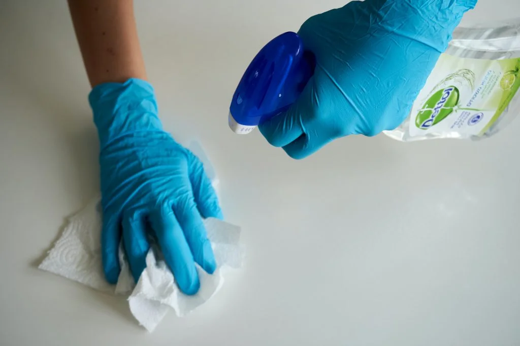 a person wearing blue gloves is cleaning a white surface