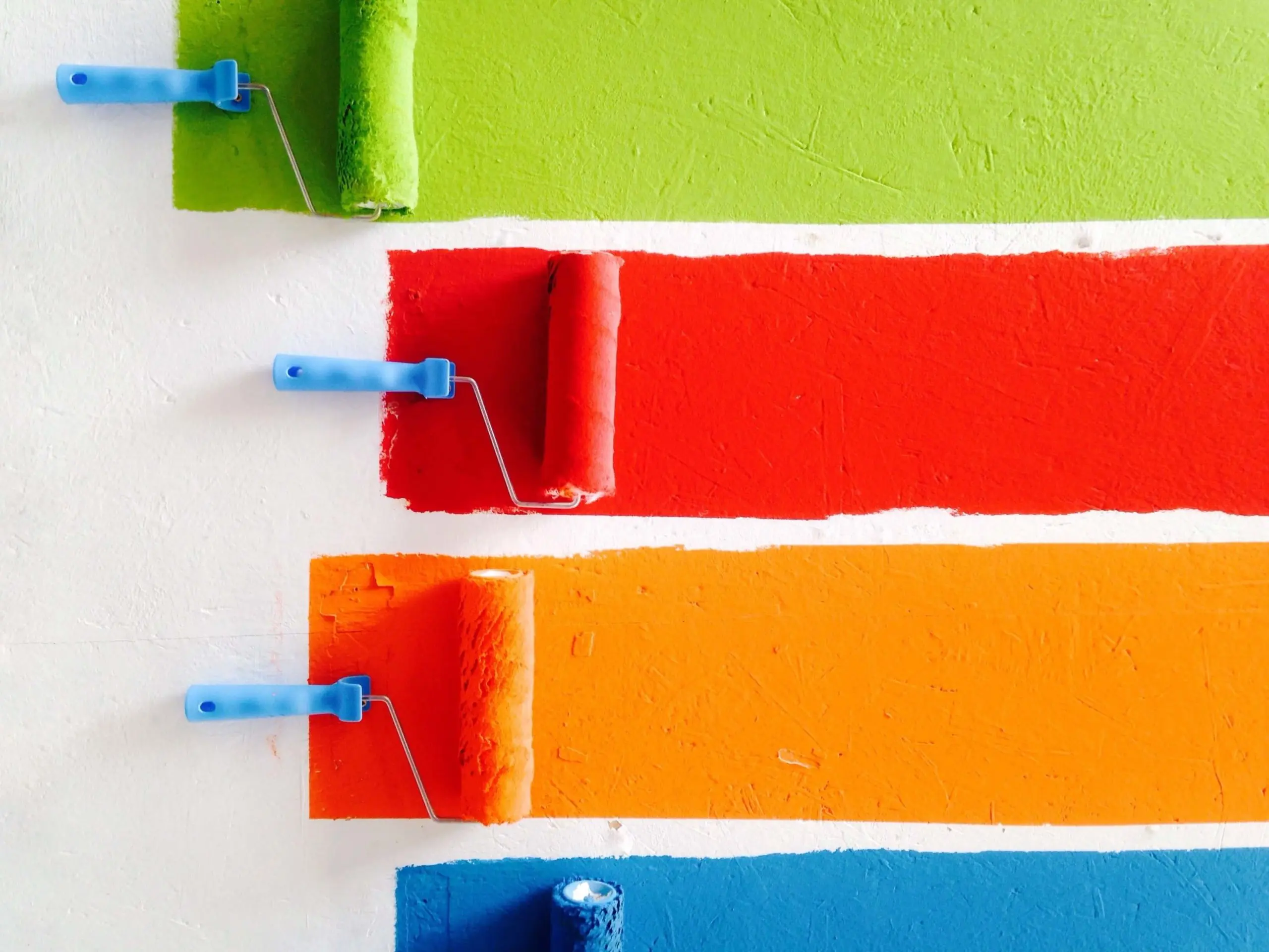 four paint rollers with different colors of paint on them