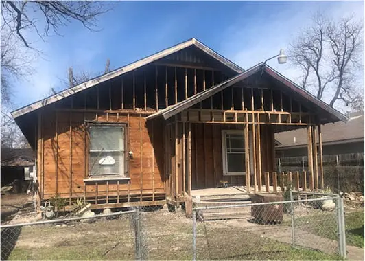a wooden house with a metal fence around it