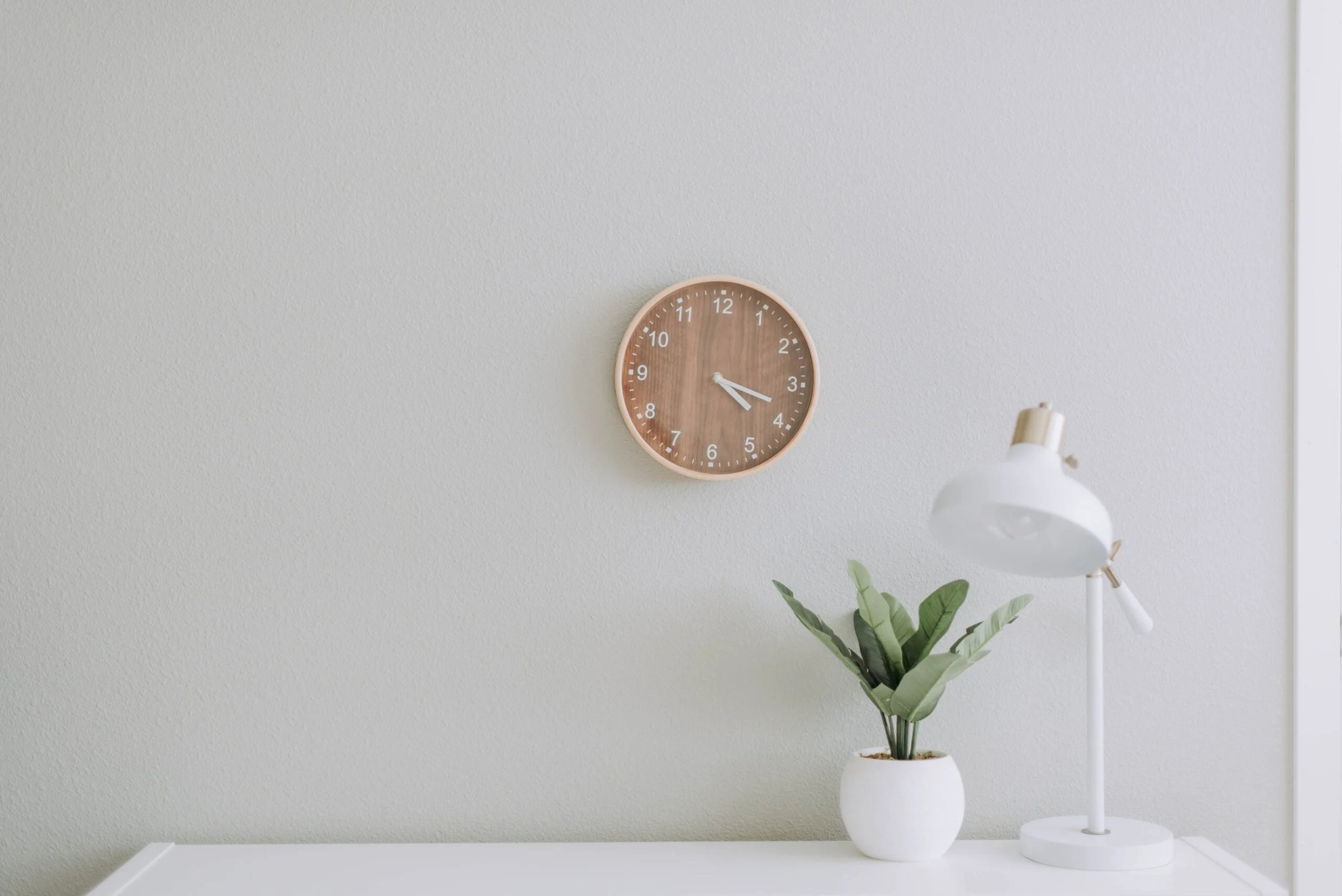 a wooden clock hanging on a white wall