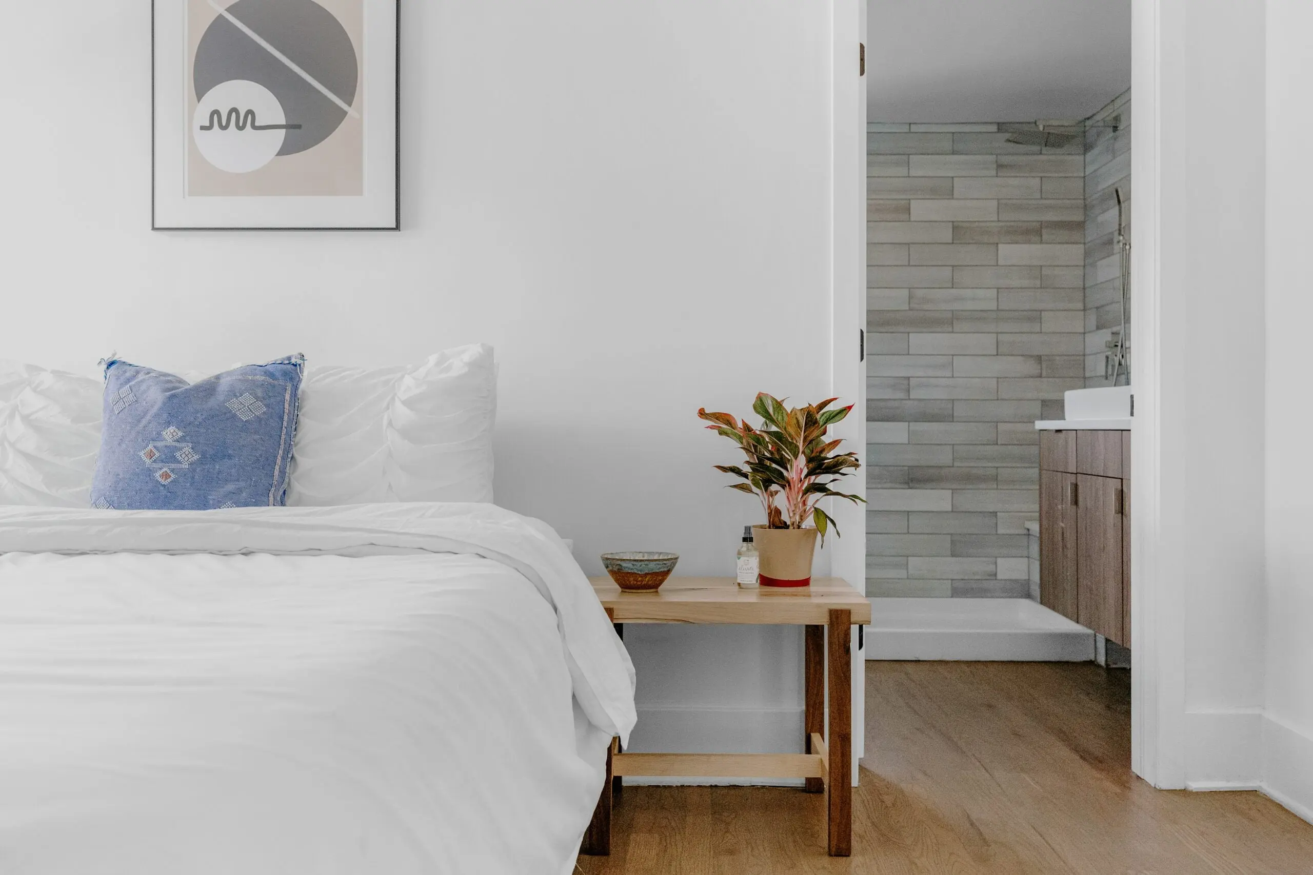 a bedroom with a plant and a picture on the wall