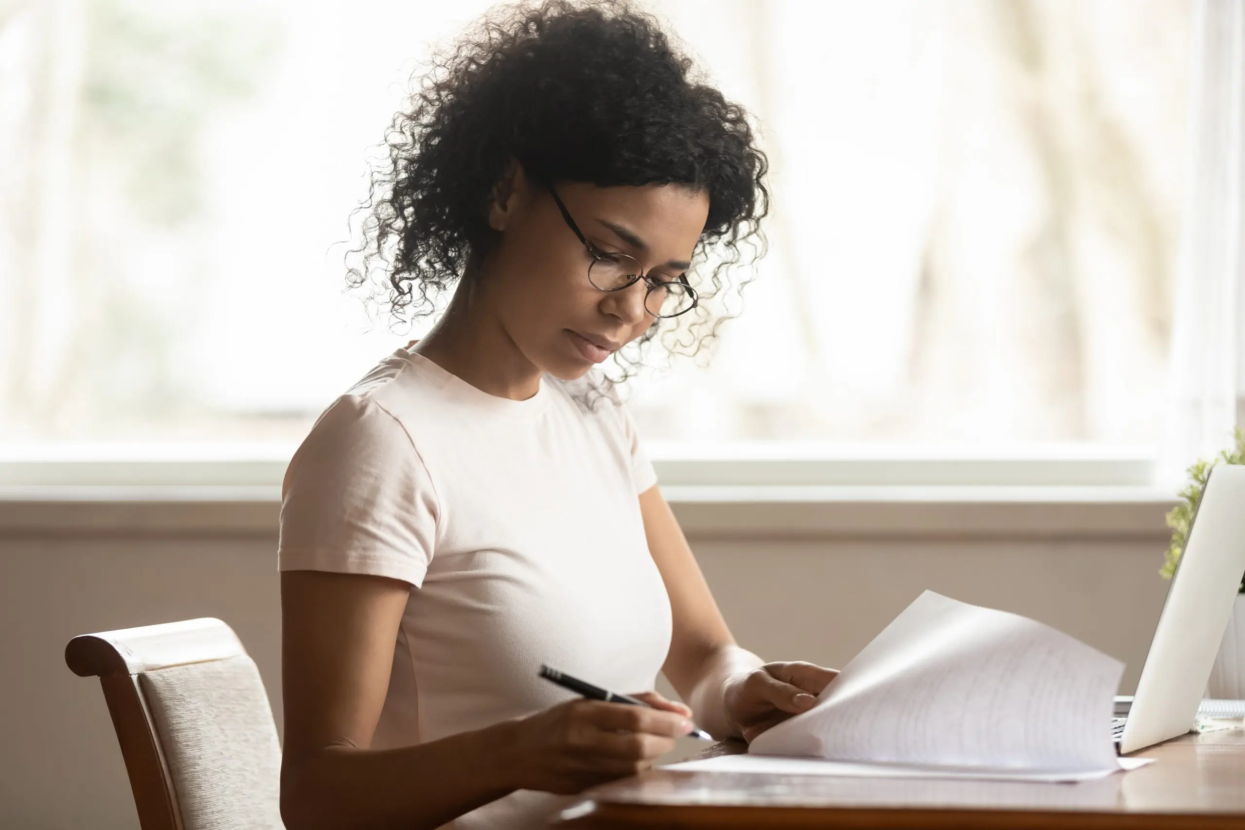 a woman wearing glasses is writing on a piece of paper