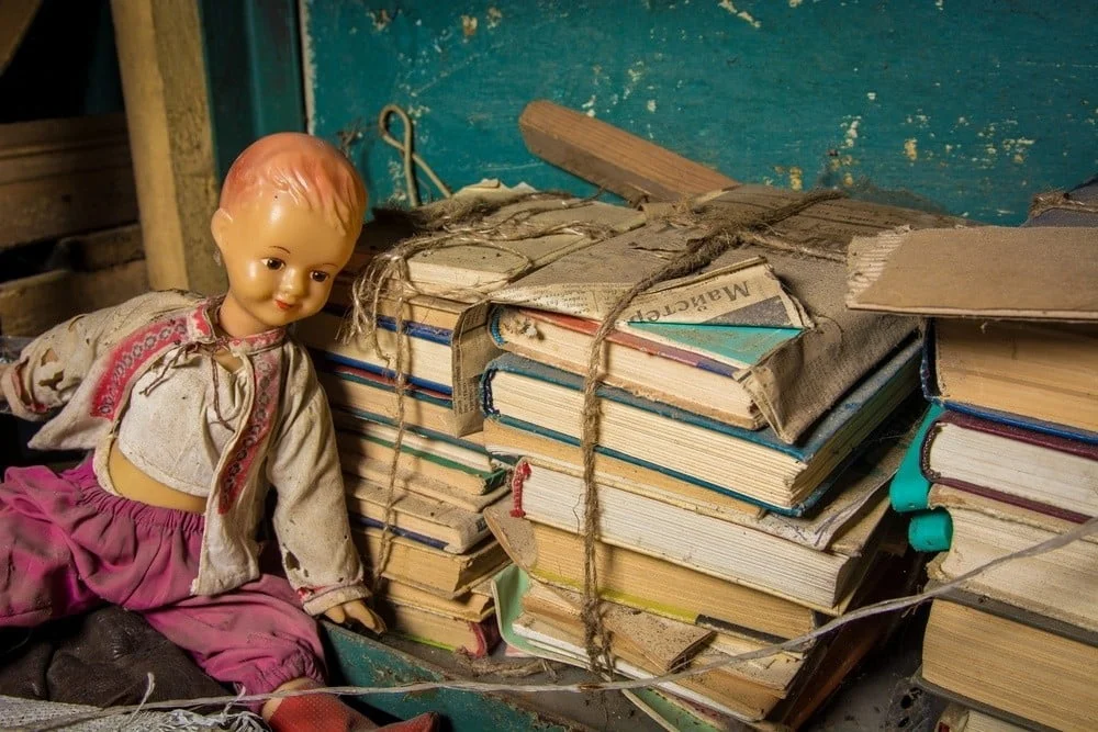 a doll sits next to a pile of books