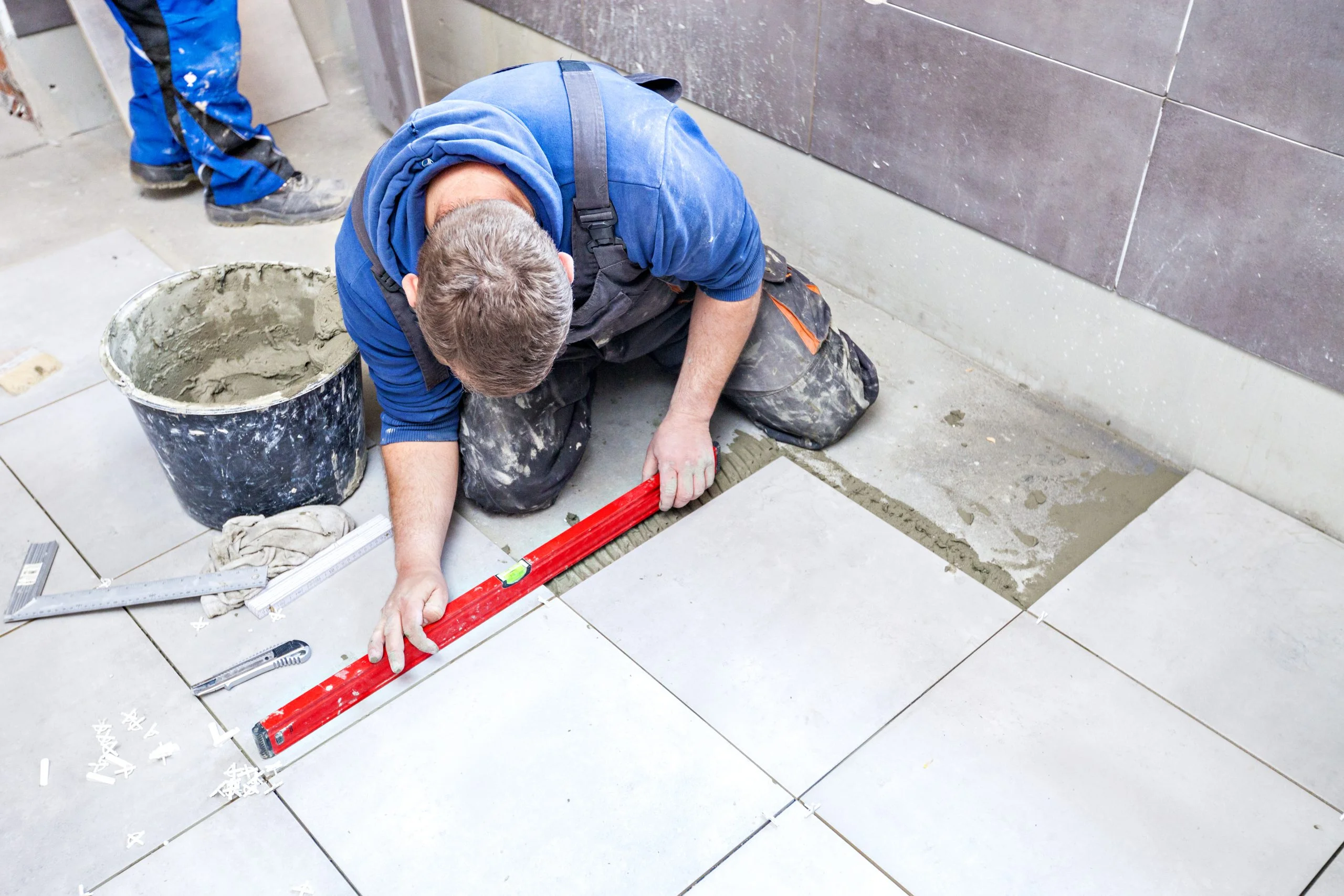 a man is measuring a tile floor with a red level