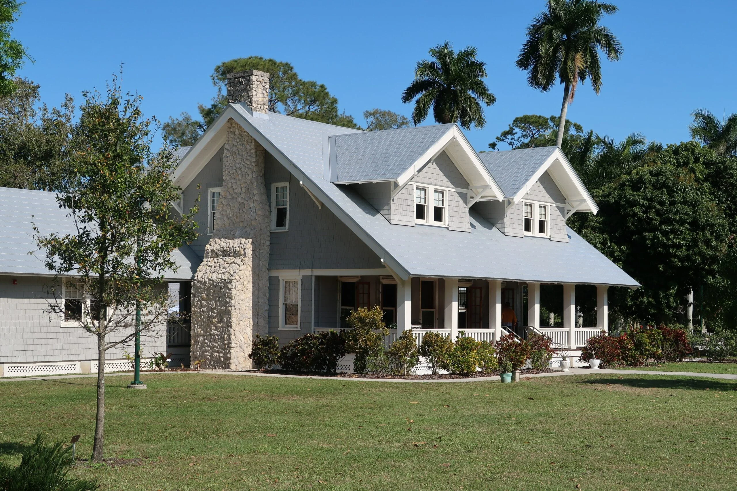 a large house with a gray roof and a stone chimney