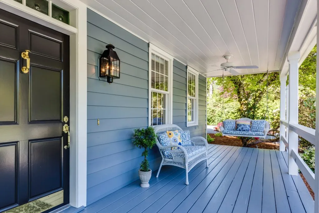 a blue house with a porch with a swing and a bench
