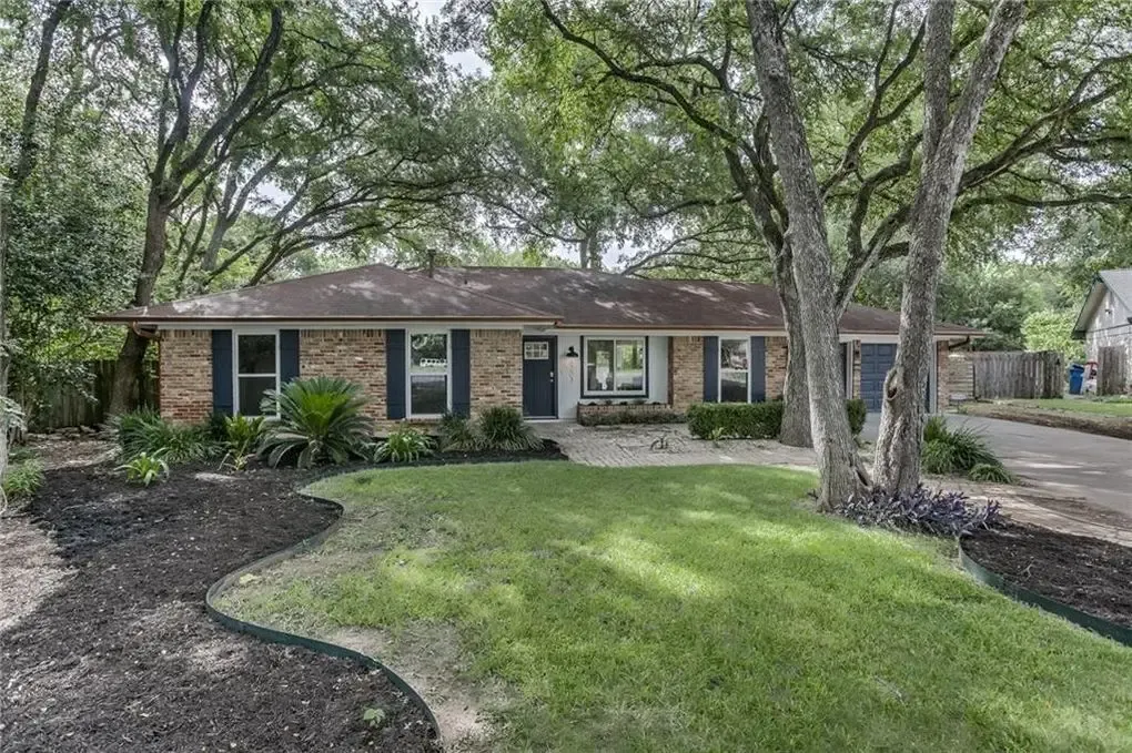 a house with a driveway and trees in front of it
