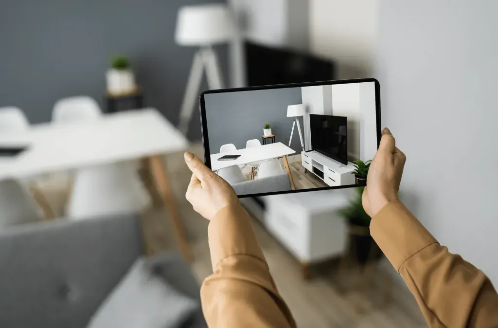 a person is holding a tablet with a picture of a living room on it