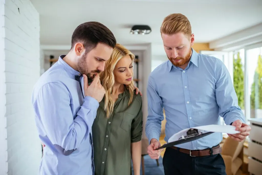 a couple looking paperwork with a real estate agent